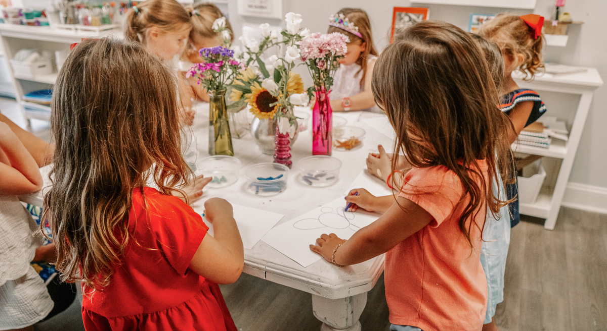 Young artists gather around an art table to make drawings in the Art House Art Studio lessons in New Bern.
